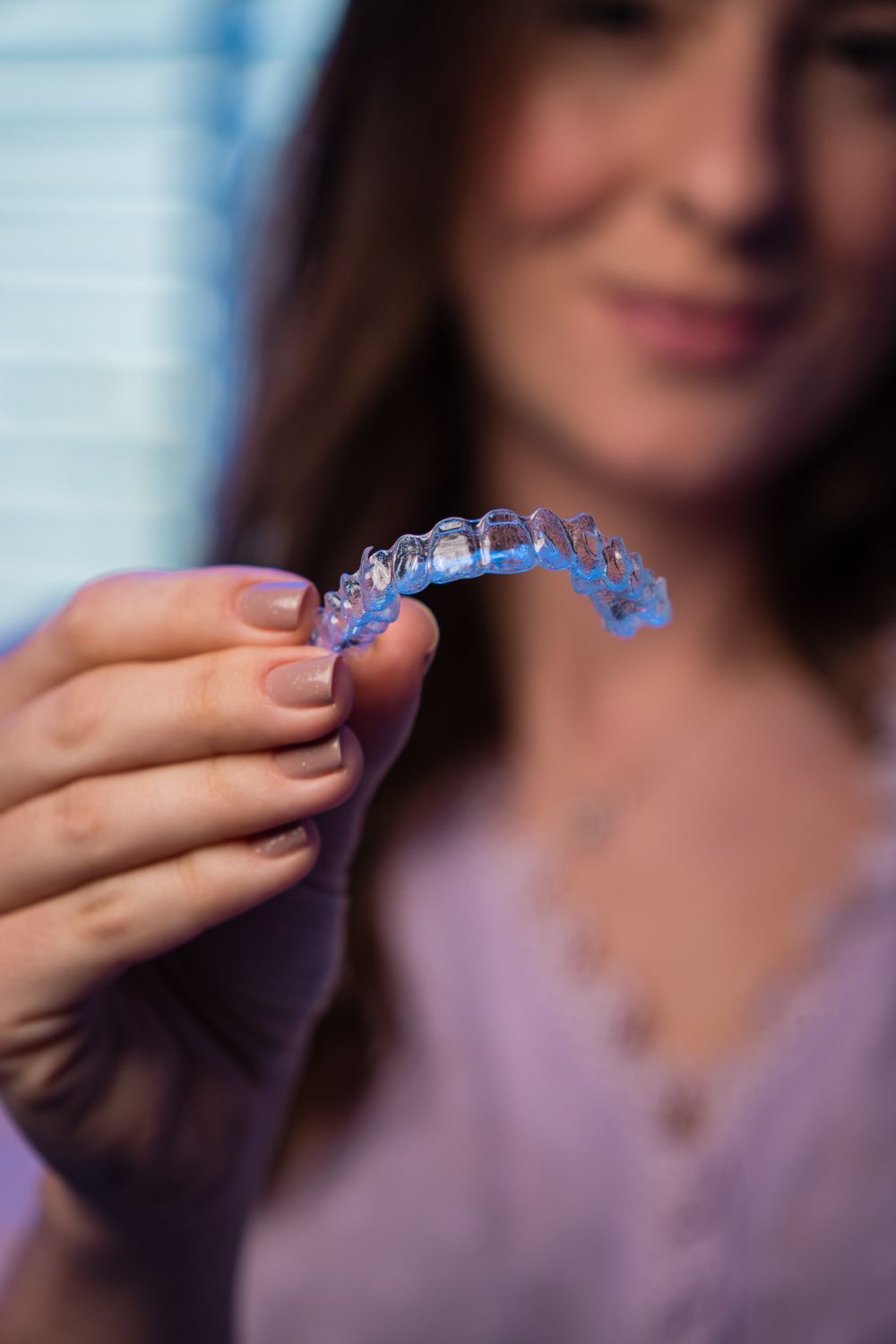 Mulher segurando um alinhador dental transparente