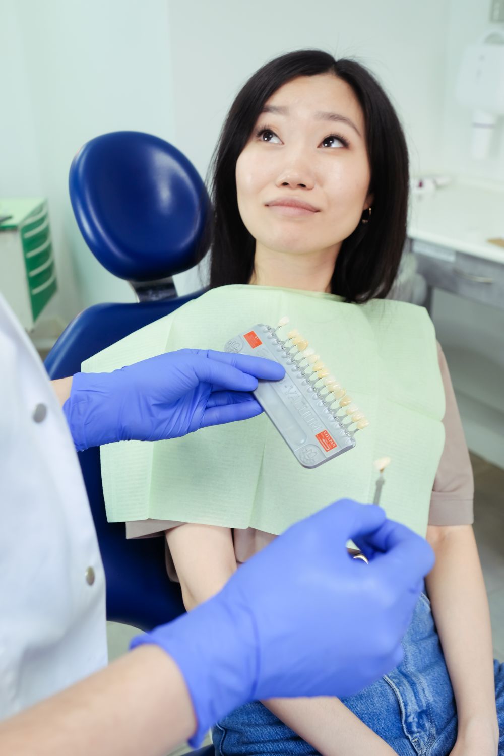 Escala de cores dos dentes sendo comparada com o sorriso de uma paciente